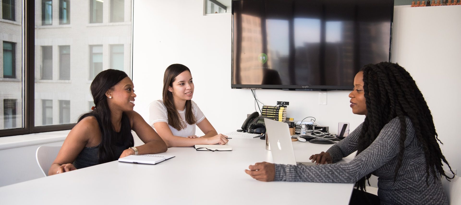 Three women sitting at a meeting table in an office